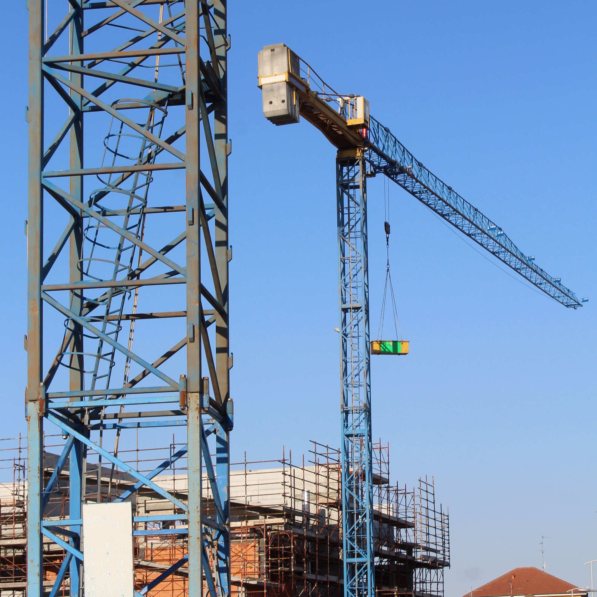 Crane at the construction site on the background of the blue sky
